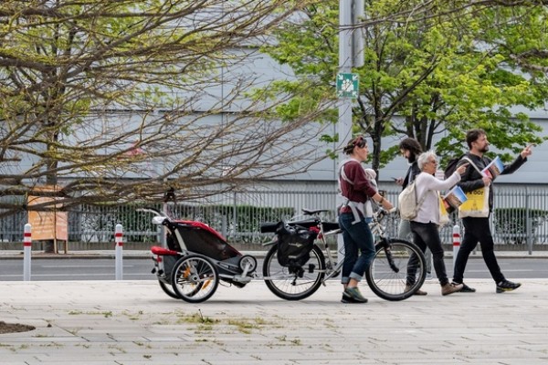 Menschen die zwischen Bäumen in der Stadt vorbei gehen